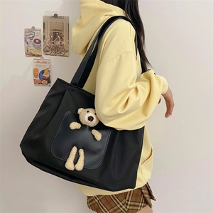 Detail of black nylon tote bag featuring a 3D plush bear on a front pocket for women