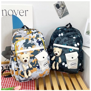 Detail of camouflage school bags with plush bear pendants and buckled front pockets