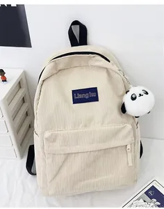 Detail of corduroy texture on cream backpack with panda charm and brand label