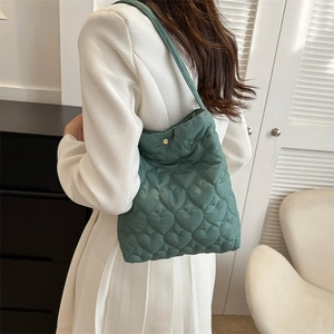Borsa tote verde muschio trapuntata a cuore con chiusura dorata indossata dalla modella