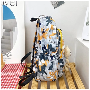 Detail view of camouflage kids backpack with yellow zippers and a cute teddy bear charm