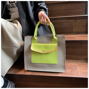 Detail of grey-white tote bag with contrasting neon green handles and pocket on stairs