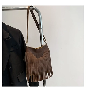 Detail of a brown fringe crossbody phone bag with pebble leather texture and long tassels