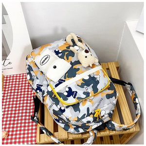 Detail view of camouflage student backpack with plush bear charm and fashion pouches
