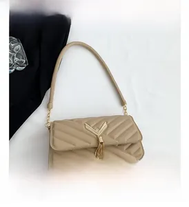Detail view of beige quilted shoulder bag with golden V-shaped hardware and metallic tassel
