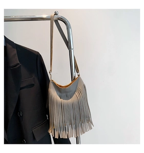 Detailed view of grey fringe crossbody bag featuring pebbled leather and long tassels