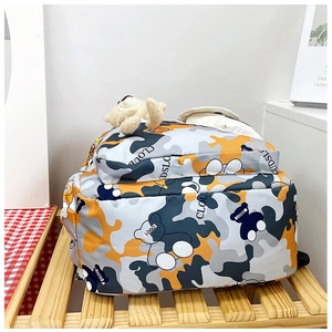 Detail of camouflage backpack with bear patterns, plush charm, and cloud print design