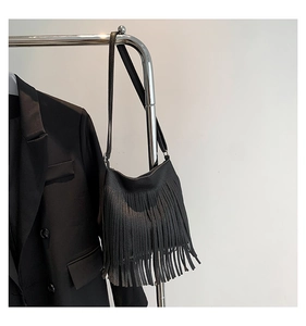 Detail of black pebbled leather crossbody bag featuring bohemian style long fringe accents