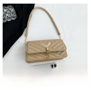 Detailed view of beige quilted shoulder bag with V-shaped stitching and golden tassel hardware