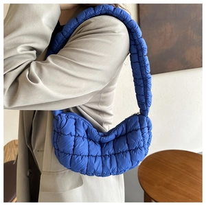 Detail of royal blue quilted puffer bag showing micro-glossy nylon and padded shoulder strap