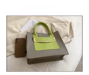 Detail view of a two-tone tote bag with dark grey body and vibrant lime green handles