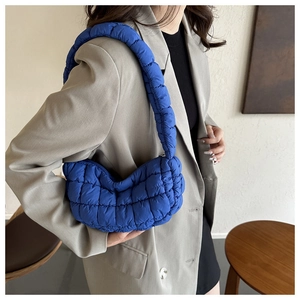 Chic royal blue quilted cloud bag shown on shoulder over a light khaki blazer