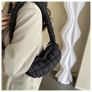 Detail of black quilted cloud bag with pleated texture and silver zipper shown on model