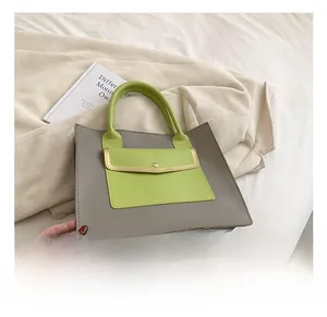 Detail view of grey faux leather tote bag with vibrant neon green handles and magnetic front pocket