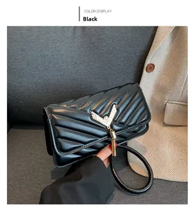 Detail of black quilted leather shoulder bag with gold V-buckle and tassel on sofa