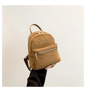 Détail du mini sac à dos en daim marron montrant l'étiquette mode et la texture du zip