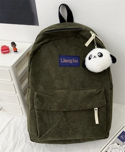 Detailed macro view of dark green corduroy texture and plush panda pendant on the backpack