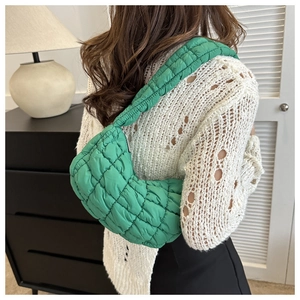 Quilted lime green shoulder bag in puffy nylon material worn by model in home setting