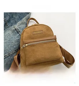 Détail d'un sac à dos marron en daim avec fermeture dorée sur fond en tissu denim