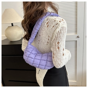 Close-up of a quilted purple cloud bag showing the puffy texture and crossbody wear