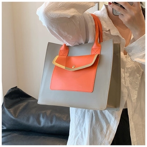 Detail of grey PU leather tote bag with orange handles and contrasting front pocket