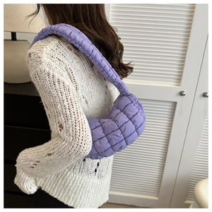 Close-up of quilted purple crescent shoulder bag with soft pleated texture and strap