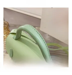 Close-up of comfortable light green leather handle with neat stitching and gold buckles