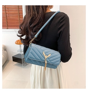Close-up of blue V-quilted shoulder bag with gold metal hardware and tassel detail
