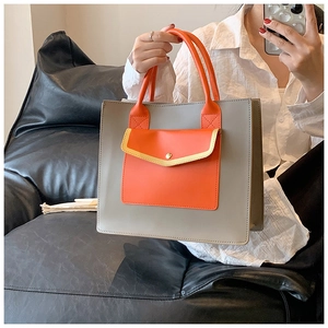 Detailed shot of grey and orange tote bag with high-quality leather and metal buckle
