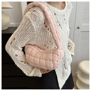 Pink quilted puffer bag with pleated cloud design shown as a crossbody on model