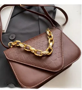 Detail of retro brown crossbody bag featuring crocodile embossed flap and gold chain