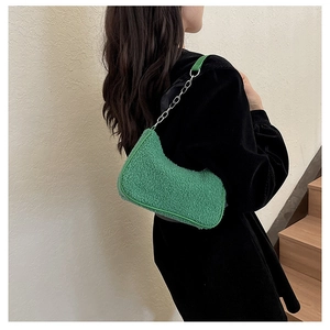 Détail d'un sac sous le bras en peluche verte avec bandoulière chaîne dorée sur mannequin
