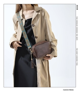 Detail of vintage brown crossbody bag featuring ethnic embroidered wide strap and leather tassels