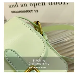Detailed view of white stitching craft and vintage gold hardware on green leather bag