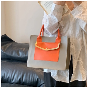 Detail of grey and orange contrast tote bag showing fine stitching and metal buckle