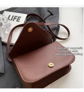 Detail view of brown leather crossbody bag with hidden magnetic clasp on grey blazer