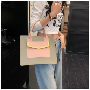 Detail view of the pink front pocket and yellow trim on the grey tote bag with metal snap
