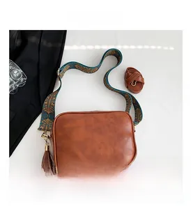 Flat lay of brown PU leather crossbody bag with ethnic weave strap and leather tassel detail