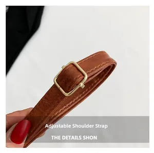 Detail of adjustable brown crocodile embossed leather shoulder strap with gold buckle
