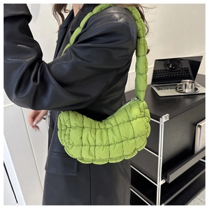Model wearing a vibrant green quilted puffer shoulder bag with a stylish pleated nylon texture