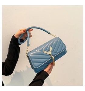 Detail of blue quilted handbag with diamond V-metal piece and golden tassel charms