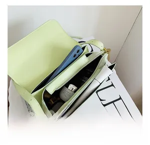 Detail view of the spacious inner compartment and zipper pocket in avocado green crossbody bag