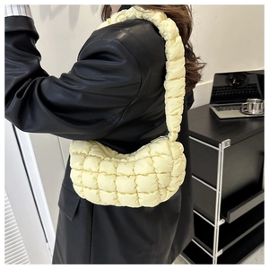 Quilted light yellow hobo bag with pleated shoulder strap shown in a modern lifestyle setting
