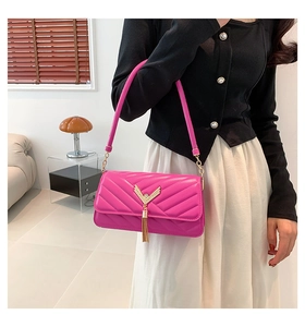 Close-up of pink quilted crossbody bag with gold V-shape metal ornament and tassel detail