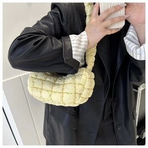 Mirror selfie showing soft light yellow quilted cloud bag worn over a black leather jacket