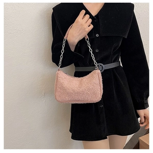 Détail du sac rose en polaire avec bandoulière chaîne argentée sur une robe noire