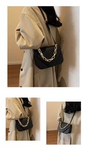 Detail of black croc-effect small square bag with chunky gold chain on beige trench coat