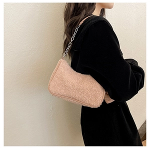 Détail du sac à bandoulière rose en peau de mouton avec chaîne argentée sur veste