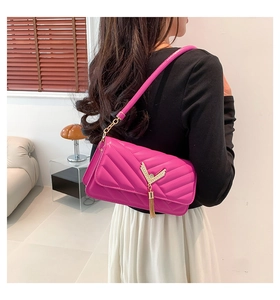 Detail of rose red quilted shoulder bag with V-shaped metal buckle and gold tassel