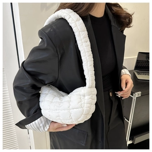 Close-up of white quilted puffer shoulder bag with padded strap and textured fabric